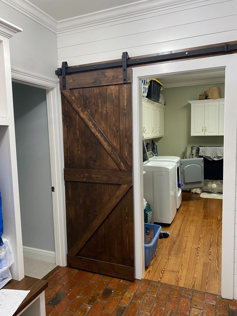 Custom Stained Barn Door Providing Stylish Access to Functional Laundry Zone