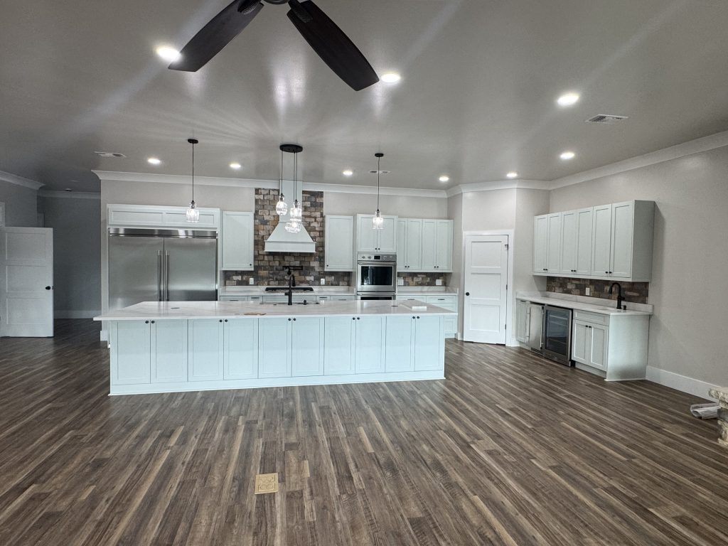 Spacious Gourmet Kitchen Featuring White Cabinetry and Stone Backsplash